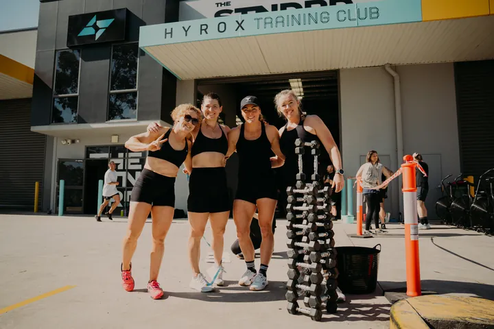 A team carrying dumbbells outside the HYROX Training Club